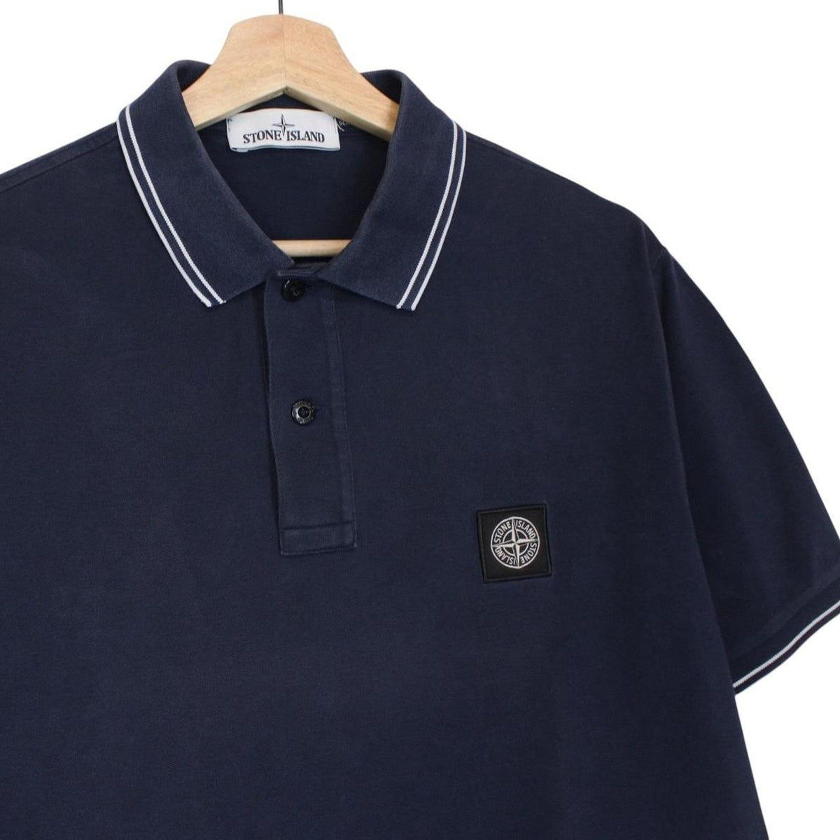 Stone Island navy blue polo shirt with embroidered compass logo and cotton material.