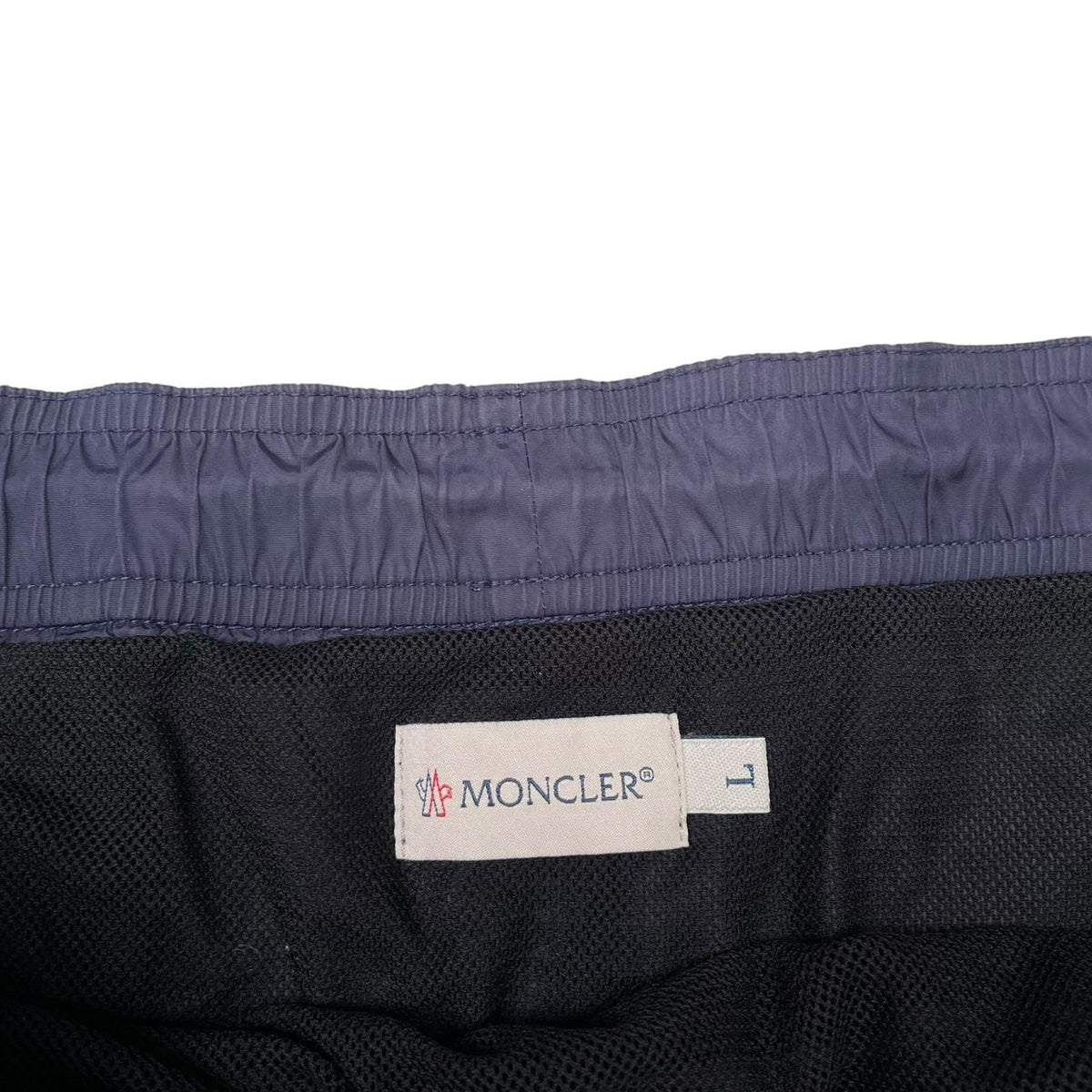 Moncler navy blue swim shorts with logo patch and lightweight nylon material.