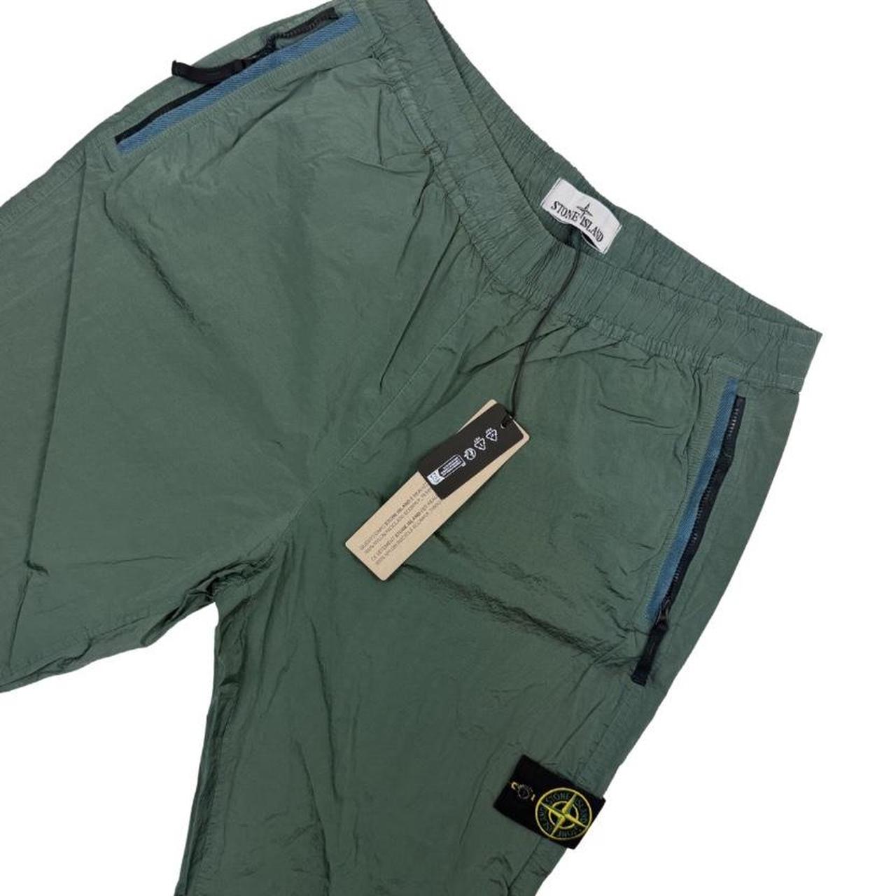 Stone Island green nylon metal trousers with logo patch and sleek finish.