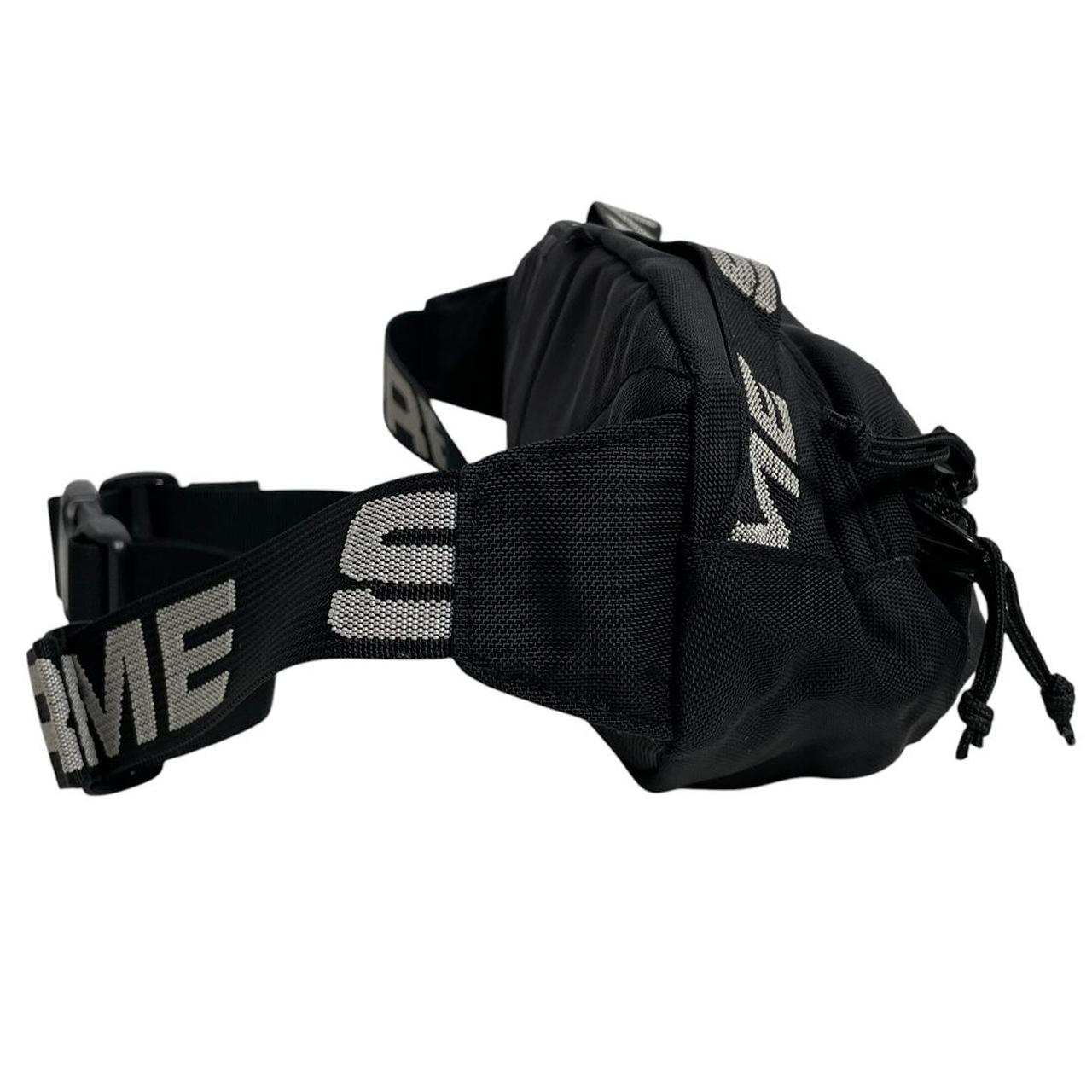 Supreme black waist bag featuring logo print and durable material.