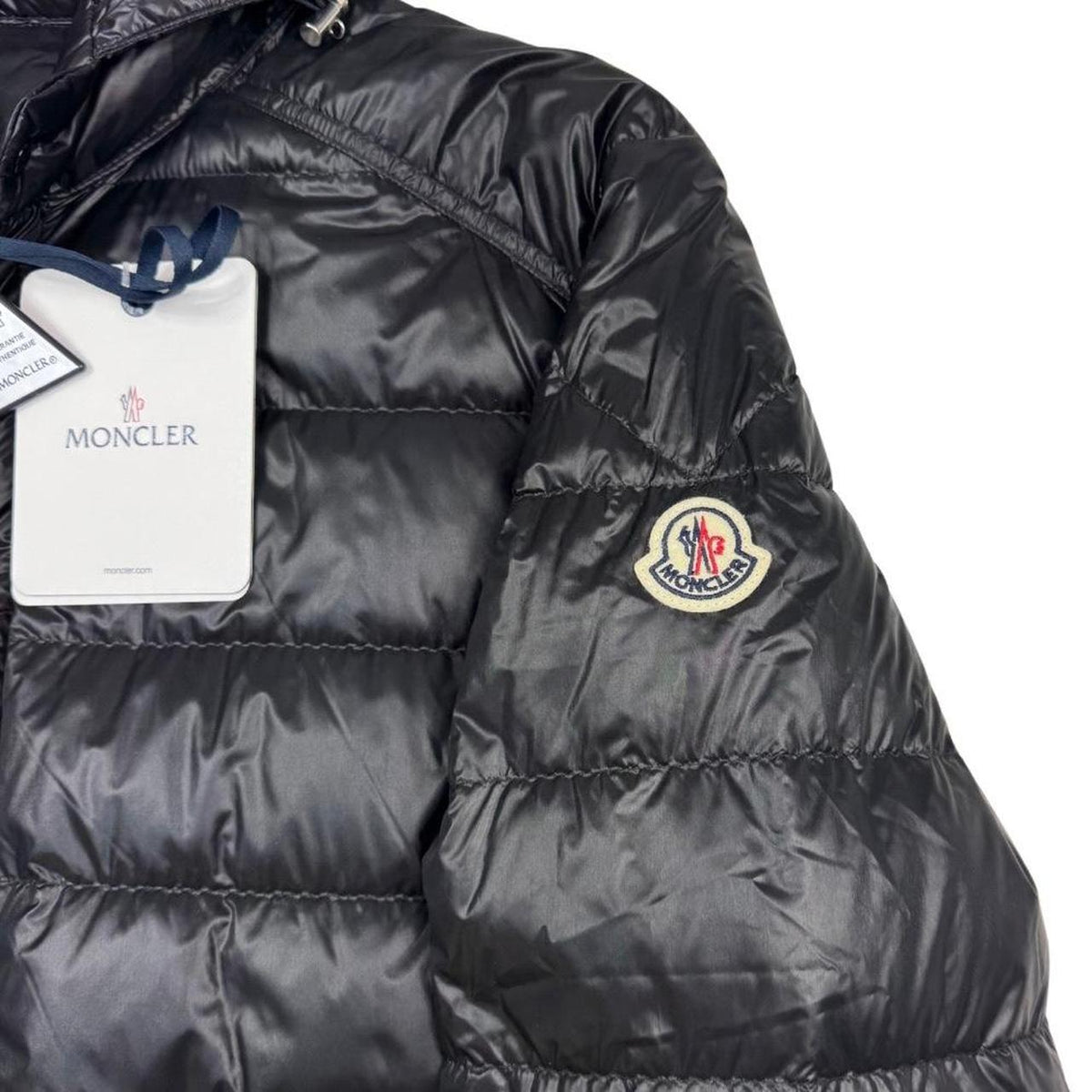 Moncler black hooded puffer jacket with logo patch and nylon material.