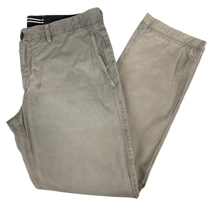 Stone Island beige slim fit cotton trousers with logo patch and visible wear marks.