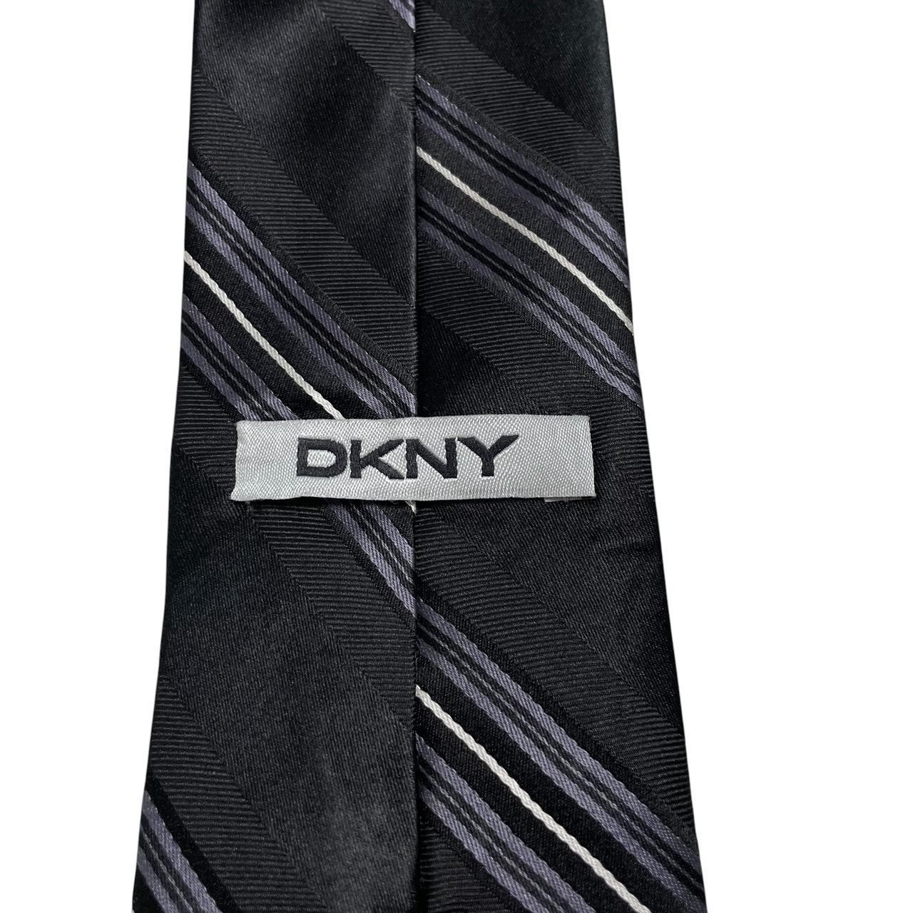 DKNY black silk tie with vintage striped pattern and logo detail.