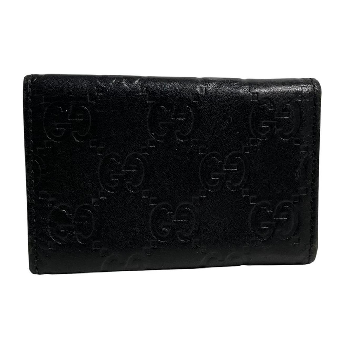 Gucci black leather key case featuring GG monogram pattern and scuffed details.