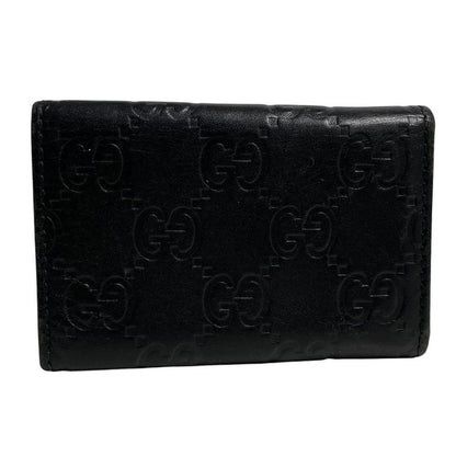 Gucci black leather key case featuring GG monogram pattern and scuffed details.