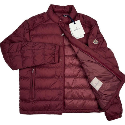 Moncler burgundy quilted down jacket with logo patch and shell material.