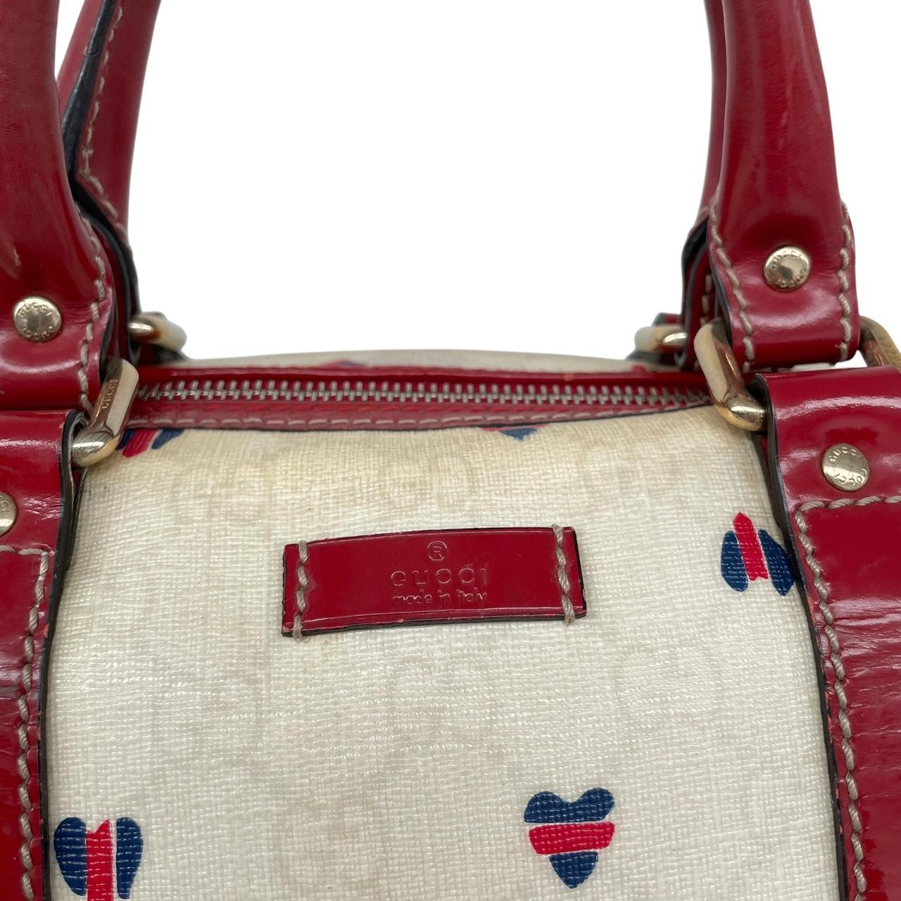 Gucci cream duffel bag with red monogram heart print and logo detailing.
