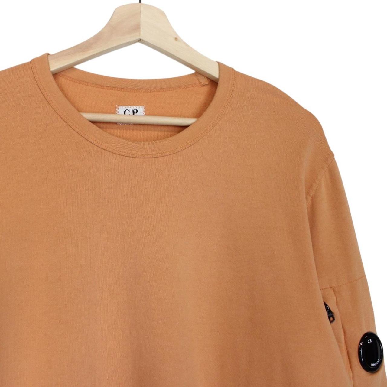 CP Company orange sweatshirt featuring goggle lens detail and soft cotton material.