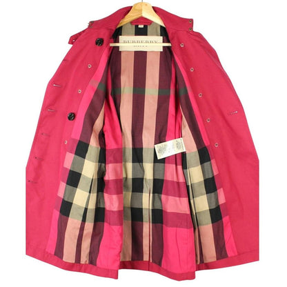 Burberry pink double breasted belted trench coat with classic check lining and logo buttons.