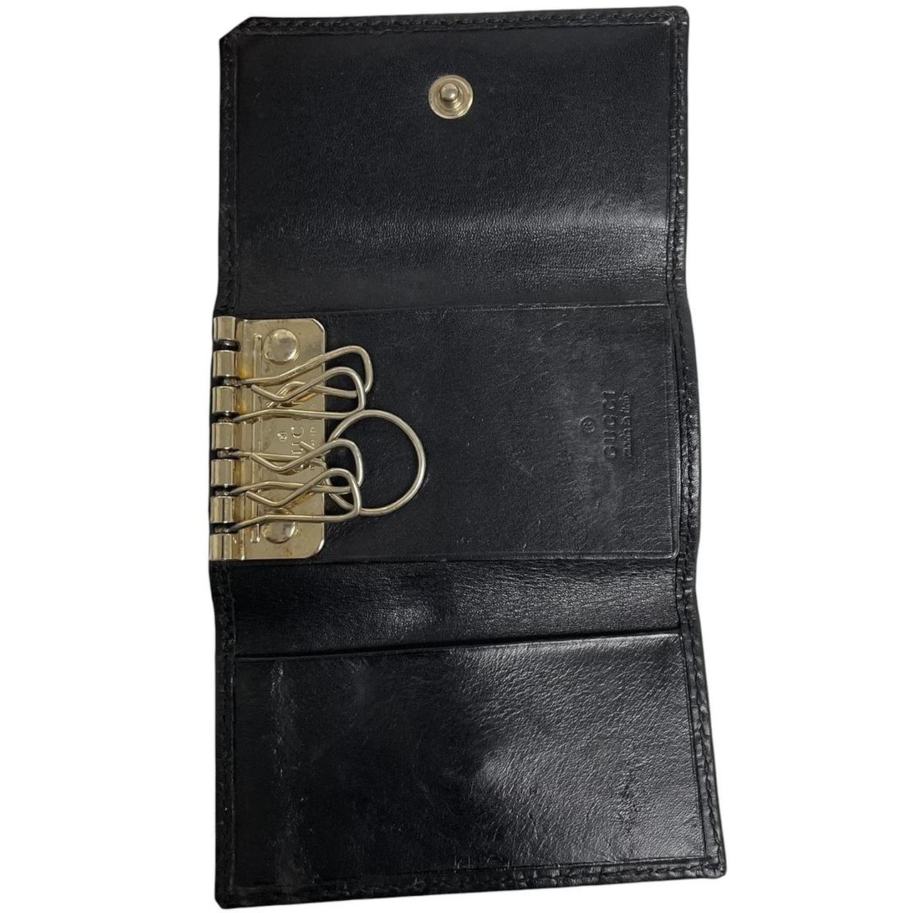Gucci black leather key case featuring GG monogram pattern and scuffed details.