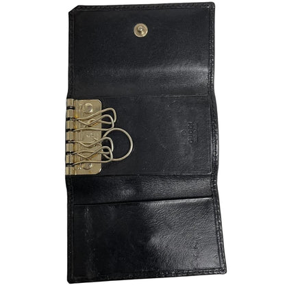Gucci black leather key case featuring GG monogram pattern and scuffed details.