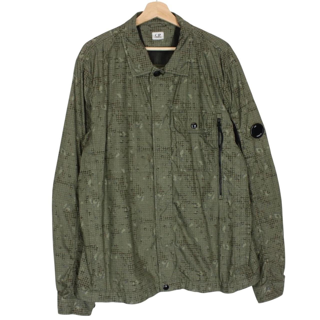 CP Company khaki green overshirt jacket with digital camouflage pattern and lens detail.