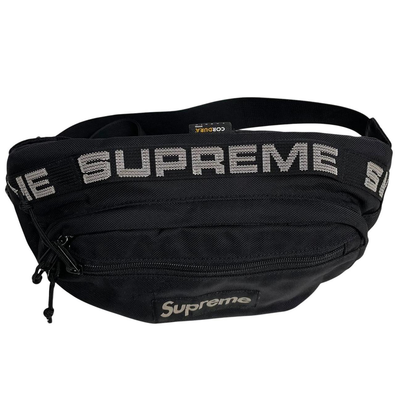 Supreme black waist bag featuring logo print and durable material.