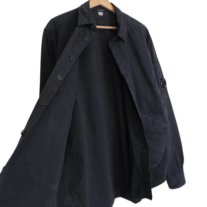 CP Company navy blue overshirt jacket with diamond pattern and lens detail.