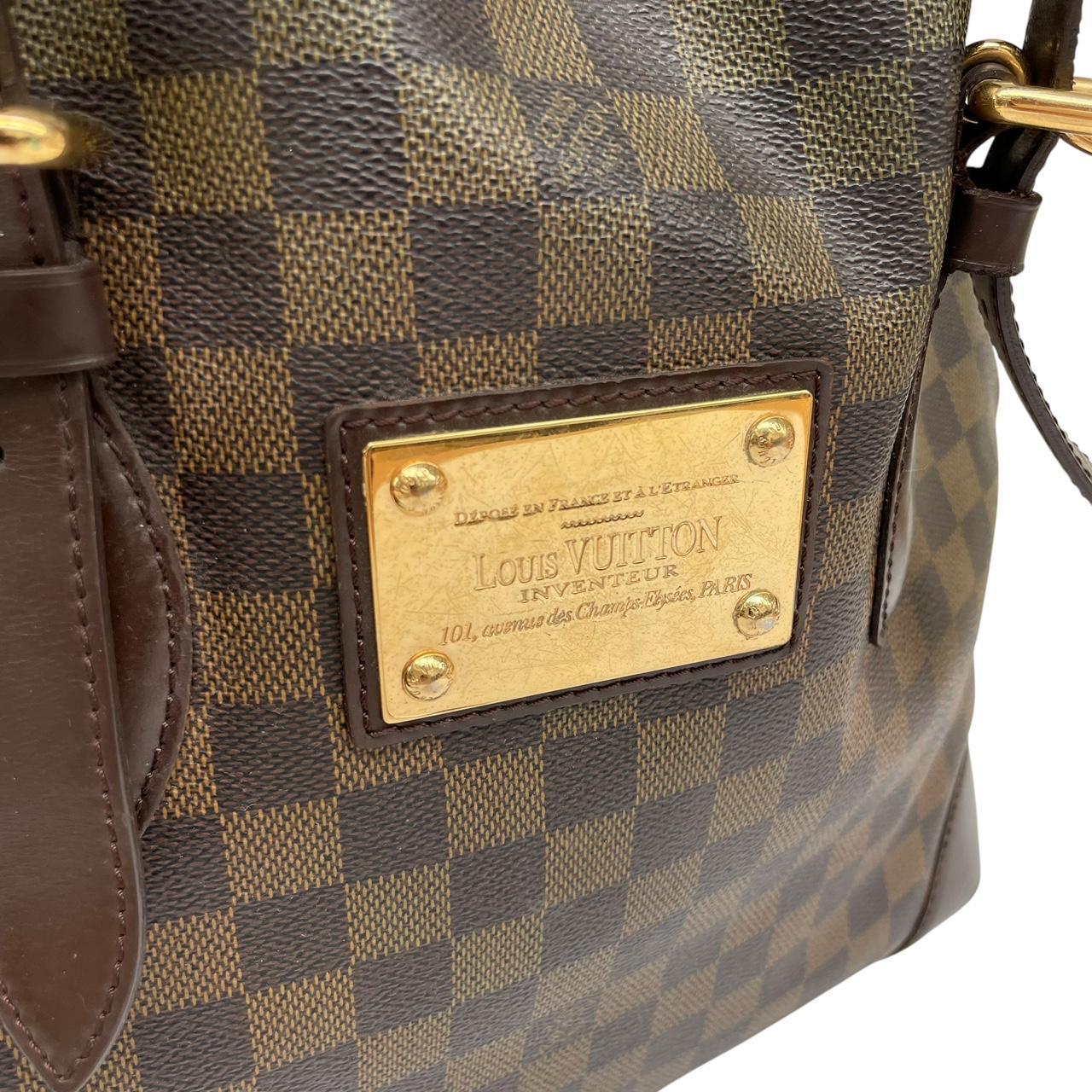 Louis Vuitton brown duffel bag with Damier Ebene pattern and logo plaque details.