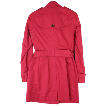 Burberry pink double breasted belted trench coat with classic check lining and logo buttons.