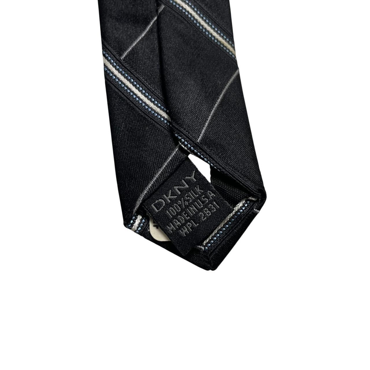 DKNY black silk tie with vintage striped pattern and logo detail.