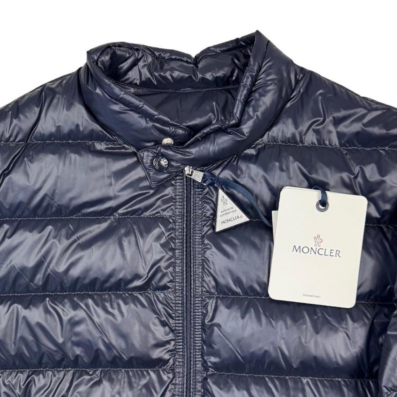 Moncler navy blue down jacket with full zip and logo patch on sleeve.