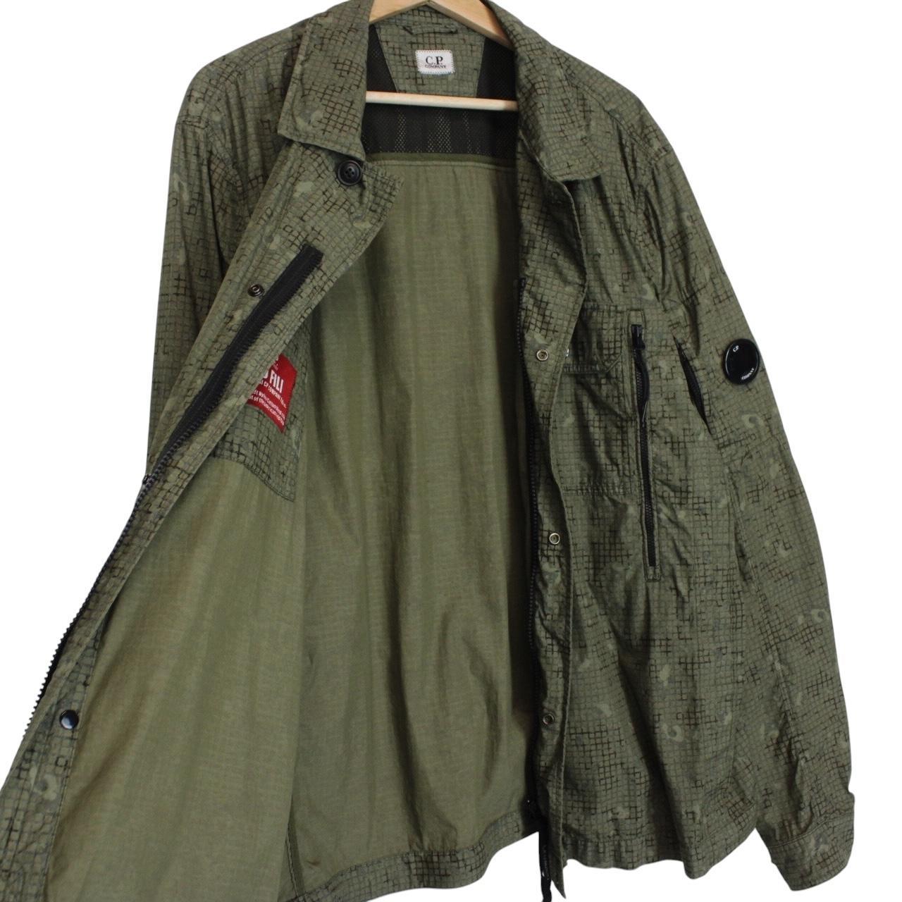 CP Company khaki green overshirt jacket with digital camouflage pattern and lens detail.