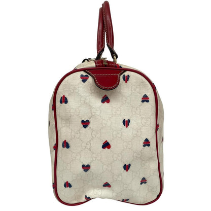 Gucci cream duffel bag with red monogram heart print and logo detailing.