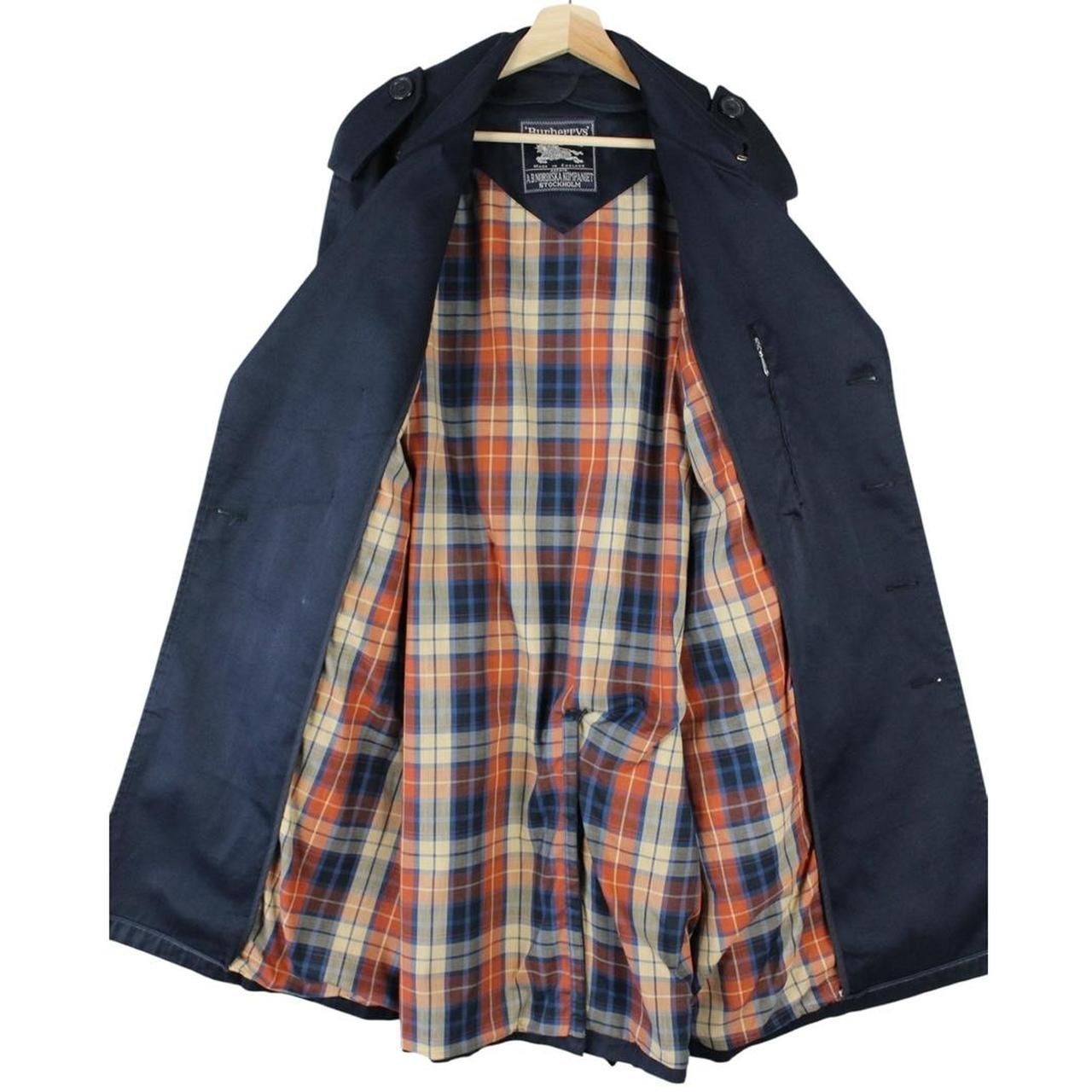 Burberry navy blue double breasted trench coat with belted waist and classic check lining.