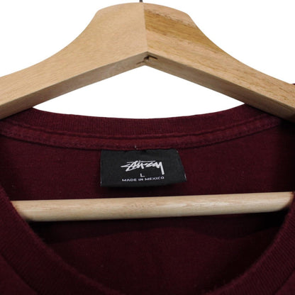 Stüssy burgundy pocket t-shirt with yellow college print and faint shoulder mark.