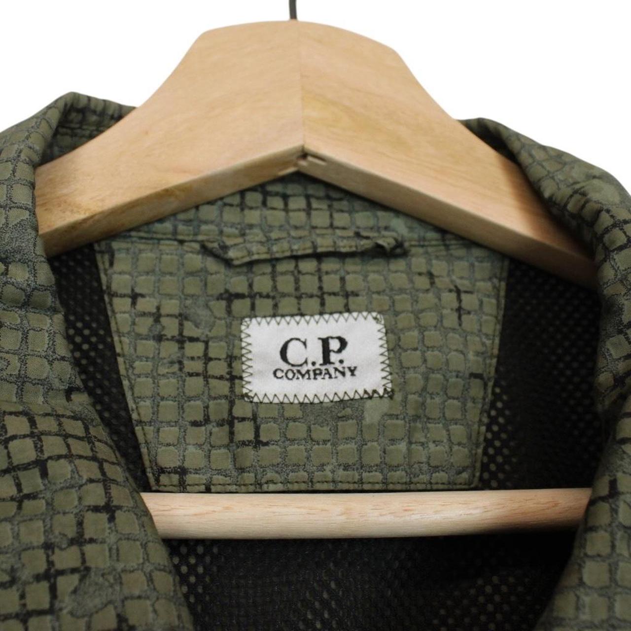 CP Company khaki green overshirt jacket with digital camouflage pattern and lens detail.