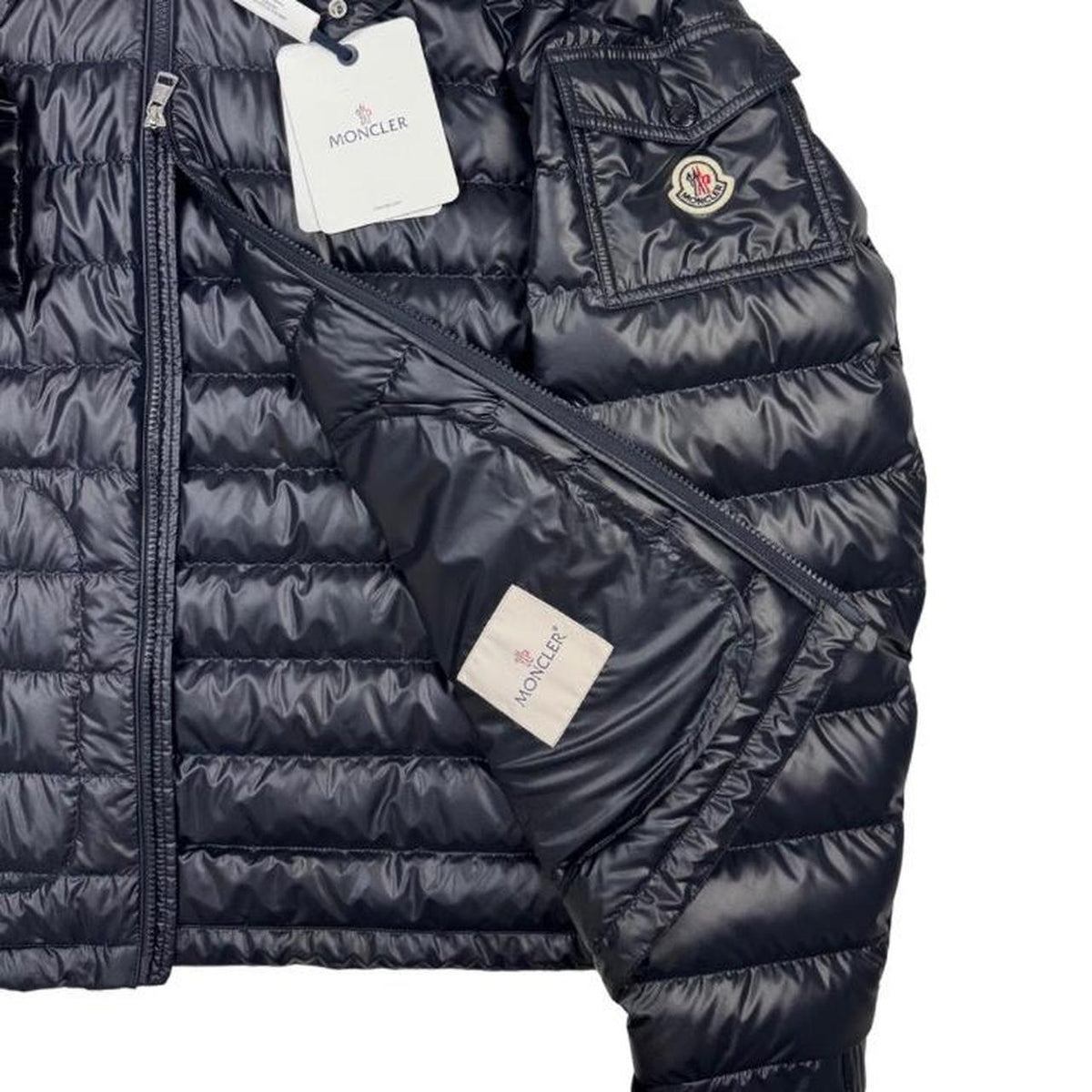 Moncler navy blue hooded puffer jacket with logo patch and nylon material.