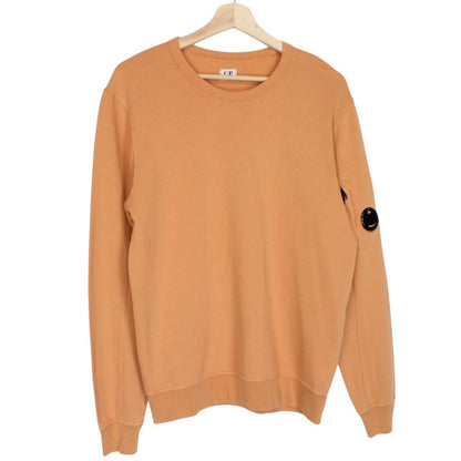 CP Company orange sweatshirt featuring goggle lens detail and soft cotton material.