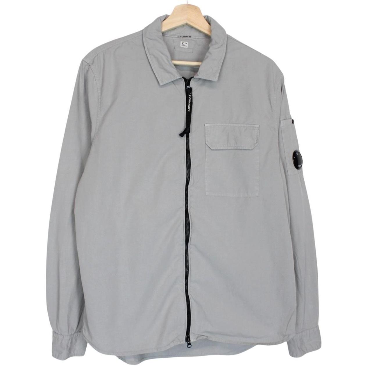 CP Company grey full zip overshirt jacket with lens detail and cotton material.