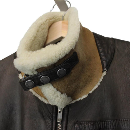 CP Company brown leather and wool shearling jacket with vintage design and logo details.