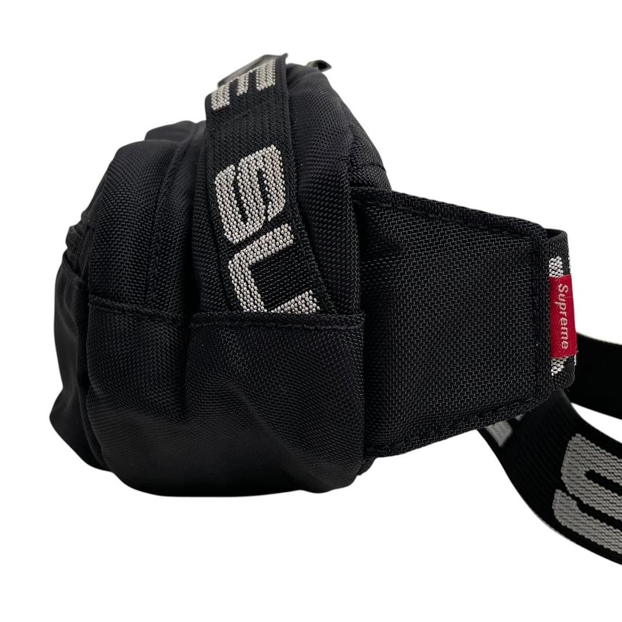Supreme black waist bag featuring logo print and durable material.