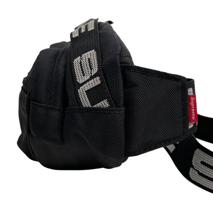 Supreme black waist bag featuring logo print and durable material.