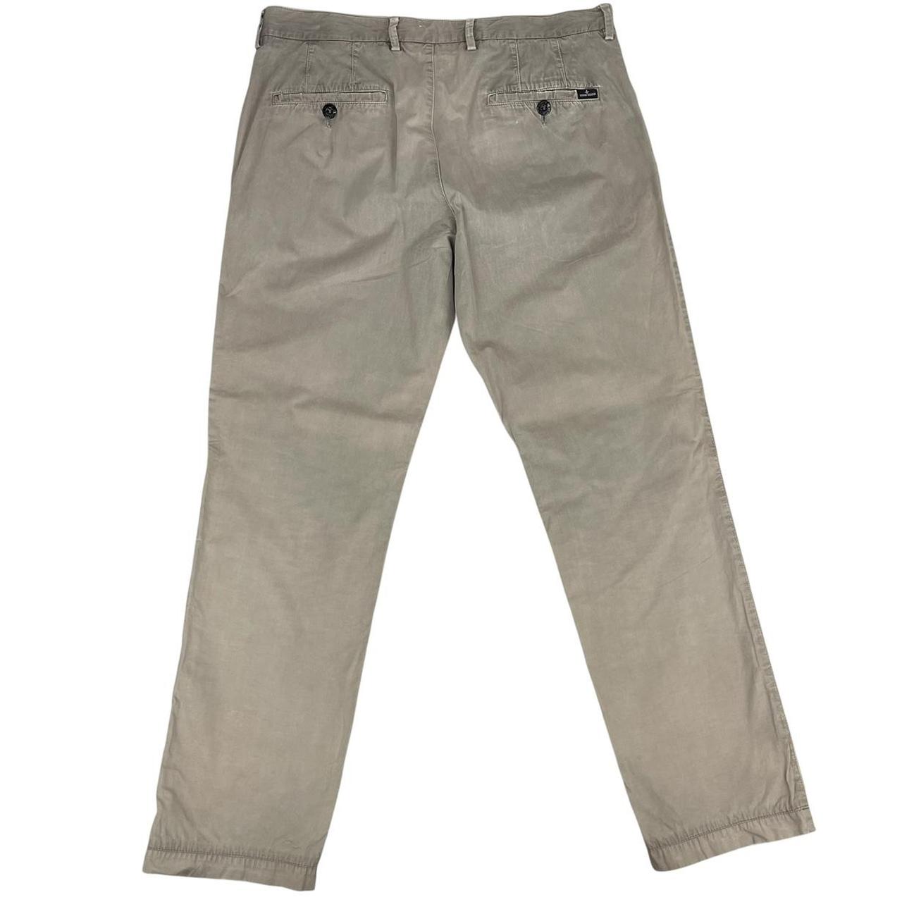 Stone Island beige slim fit cotton trousers with logo patch and visible wear marks.