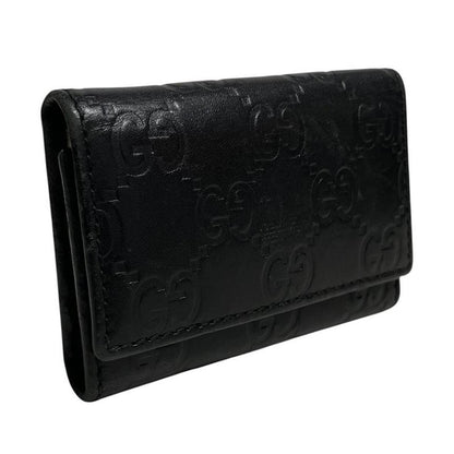 Gucci black leather key case featuring GG monogram pattern and scuffed details.