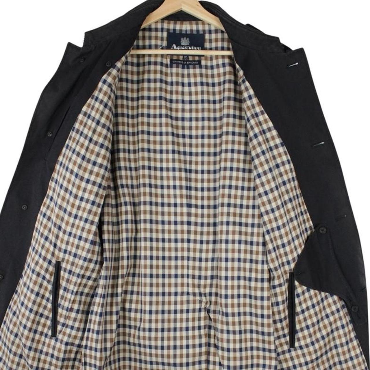 Aquascutum black trench coat with house check pattern and belted waist detail.