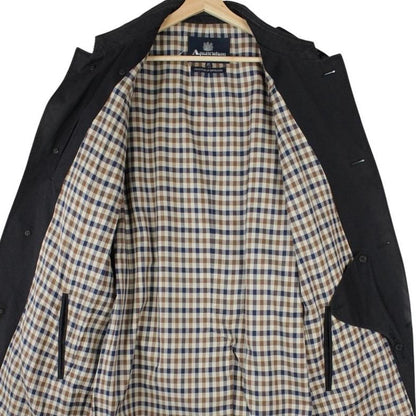 Aquascutum black trench coat with house check pattern and belted waist detail.