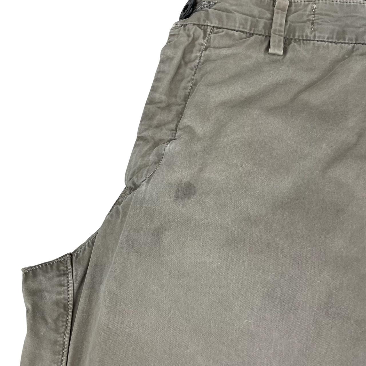 Stone Island beige slim fit cotton trousers with logo patch and visible wear marks.