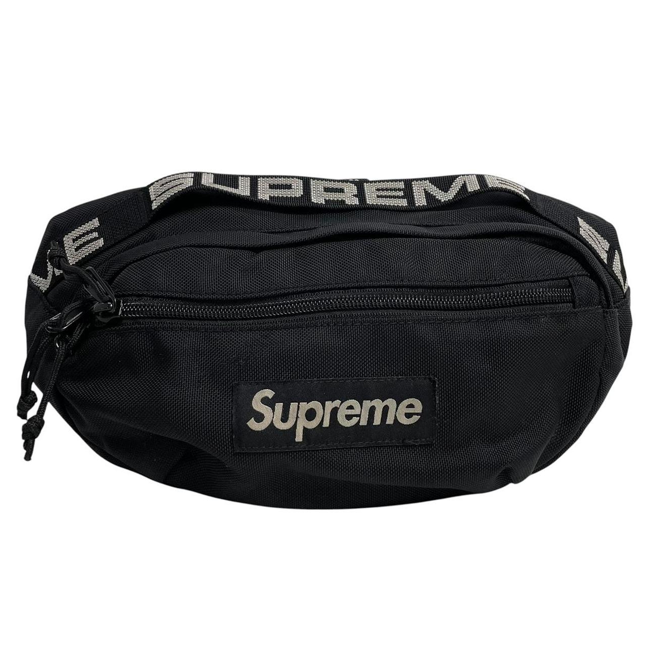 Supreme black waist bag featuring logo print and durable material.