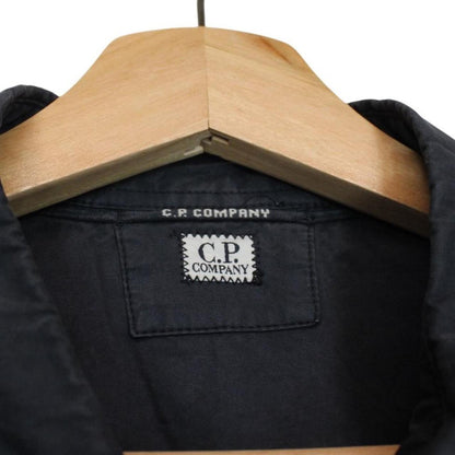 CP Company navy blue overshirt jacket with diamond pattern and lens detail.