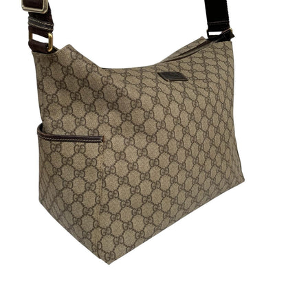 Gucci brown diaper changing bag with Supreme GG monogram and leather shoulder strap.