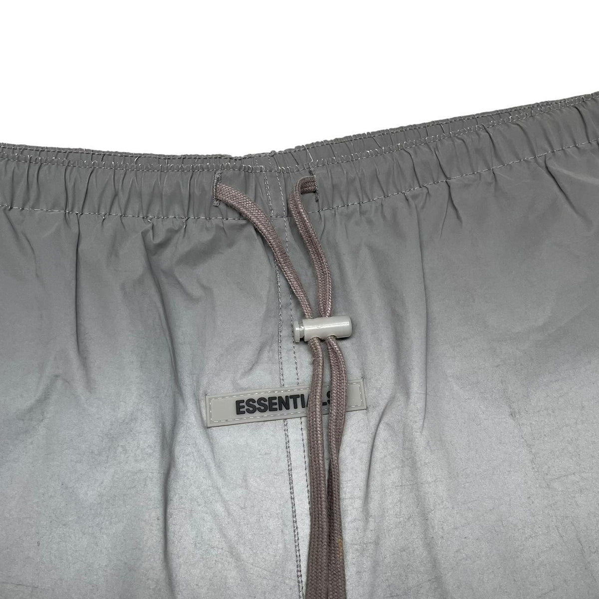 Essentials silver reflective nylon shorts with logo detail and sleek design.