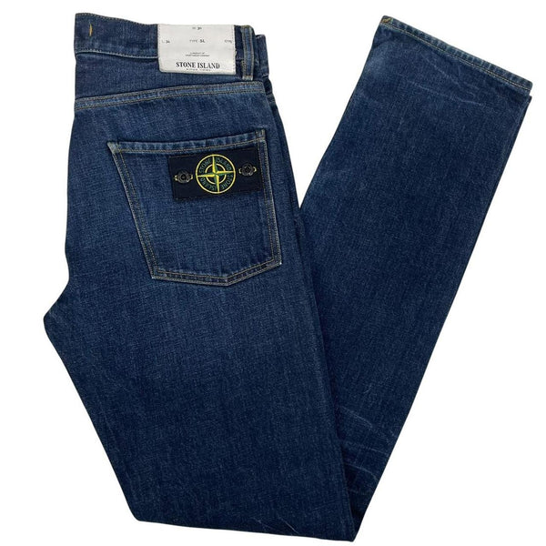 Stone Island navy blue straight jeans with logo patch and visible scuff on left knee.