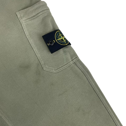 Stone Island green joggers with logo patch and cotton material, visible wear marks.