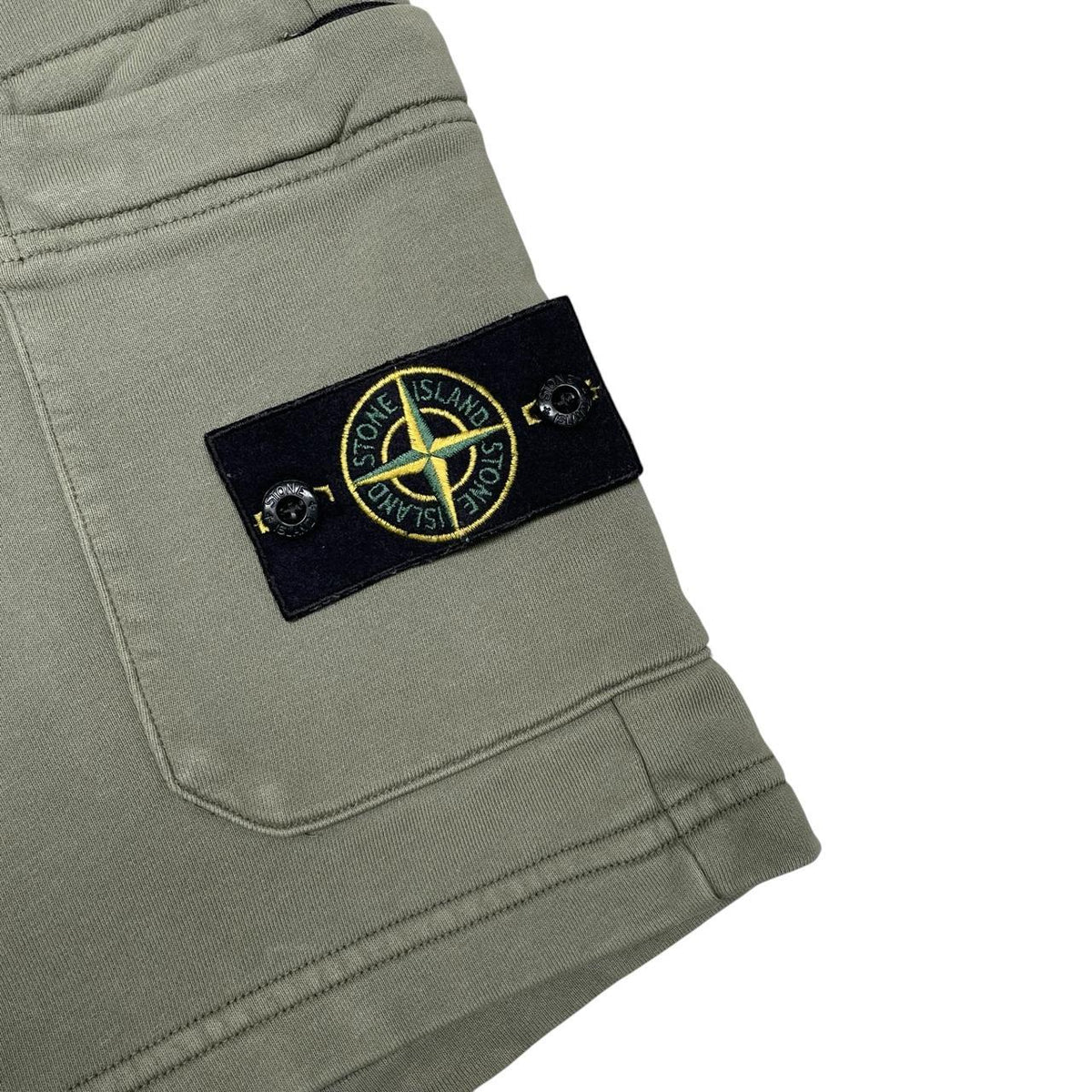 Stone Island green jogger shorts with logo patch and cotton material.