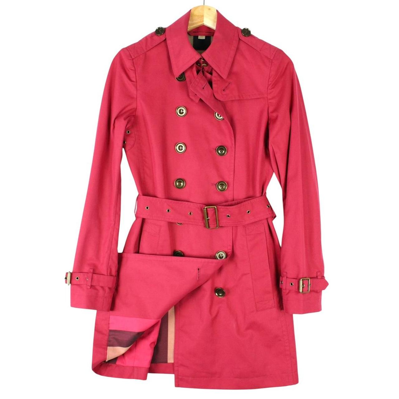 Burberry pink double breasted belted trench coat with classic check lining and logo buttons.