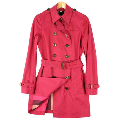 Burberry pink double breasted belted trench coat with classic check lining and logo buttons.