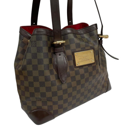 Louis Vuitton brown duffel bag with Damier Ebene pattern and logo plaque details.