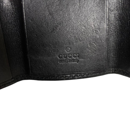 Gucci black leather key case featuring GG monogram pattern and scuffed details.