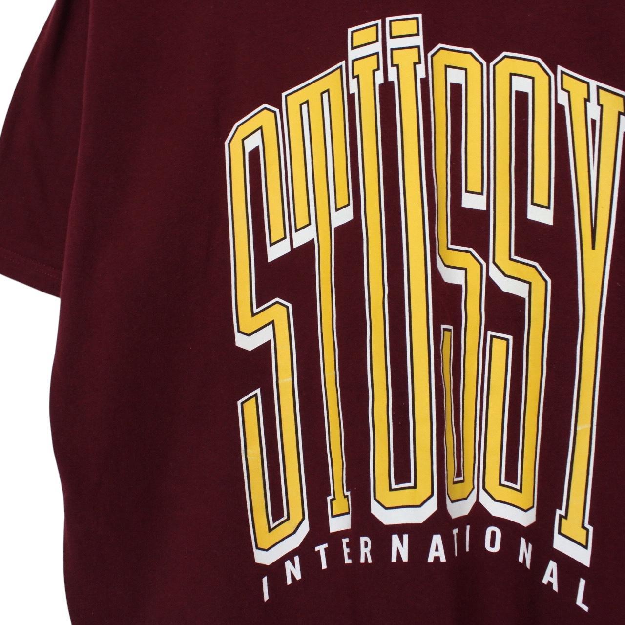 Stüssy burgundy pocket t-shirt with yellow college print and faint shoulder mark.